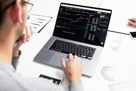 Stock Market - A Person Using a Laptop with a Chart on Screen